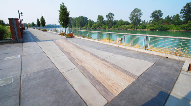 A concrete park walkway is colored by dry granular pigments and stamped with a decorative pattern
