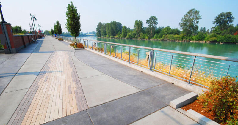 A concrete park walkway is colored by dry granular pigments and stamped with a decorative pattern