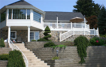 Image of a homes backyard with a retaining wall and back patio made from concrete bricks and pavers.
